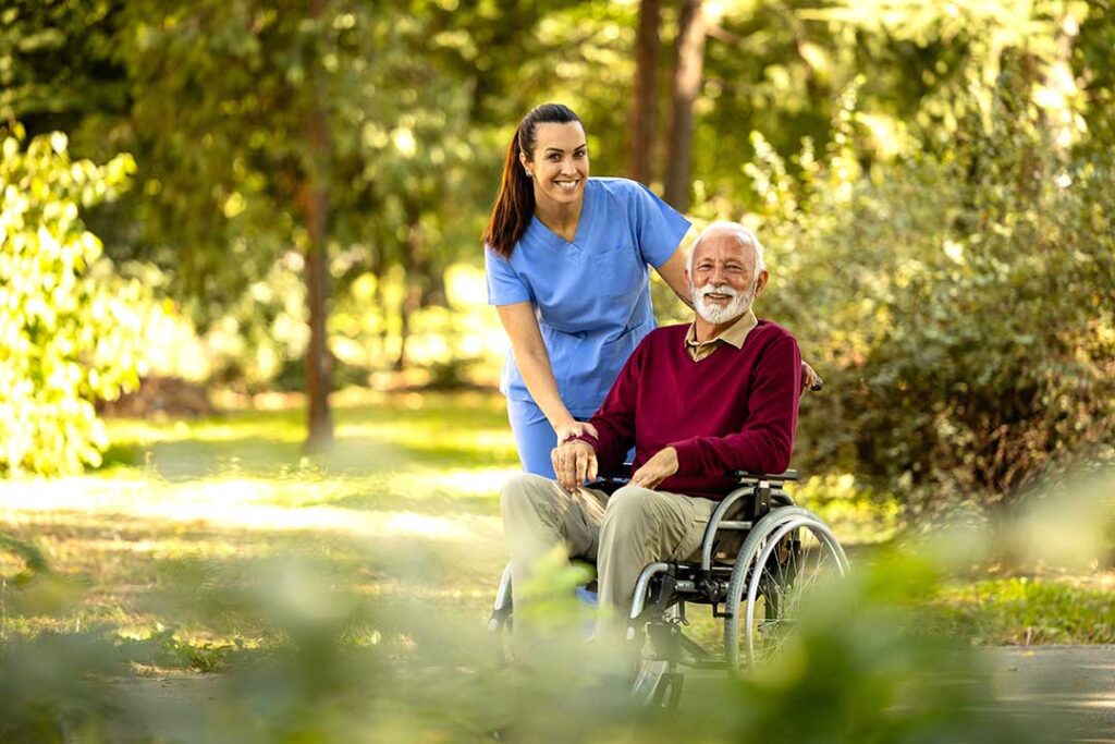 Older adults enjoy a bright assisted living common room with accessible seating and a caregiver nearby.